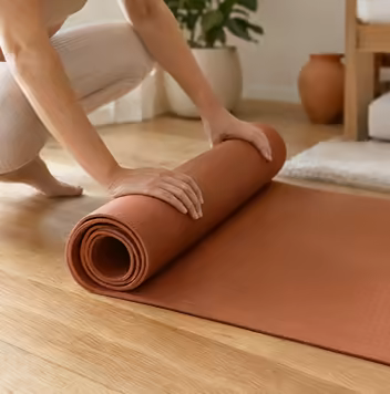 Hands rolling up a terracotta pilates mat